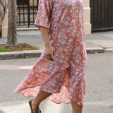 Woman in a pink and white floral dress walking on a street.
