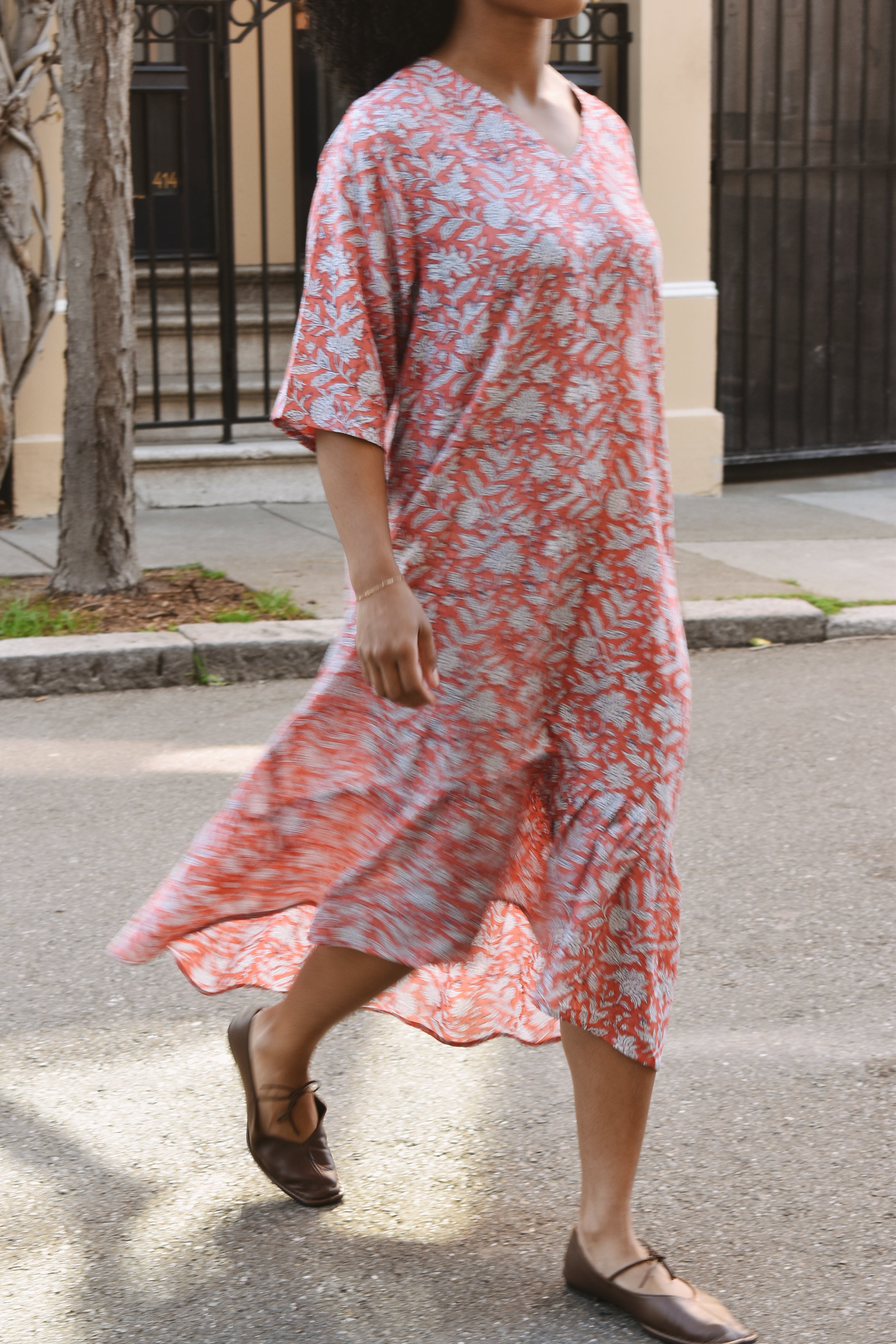 Woman in a pink and white floral dress walking on a street.