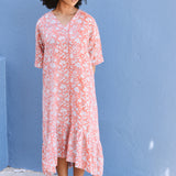 Woman wearing a pink floral dress against a blue wall