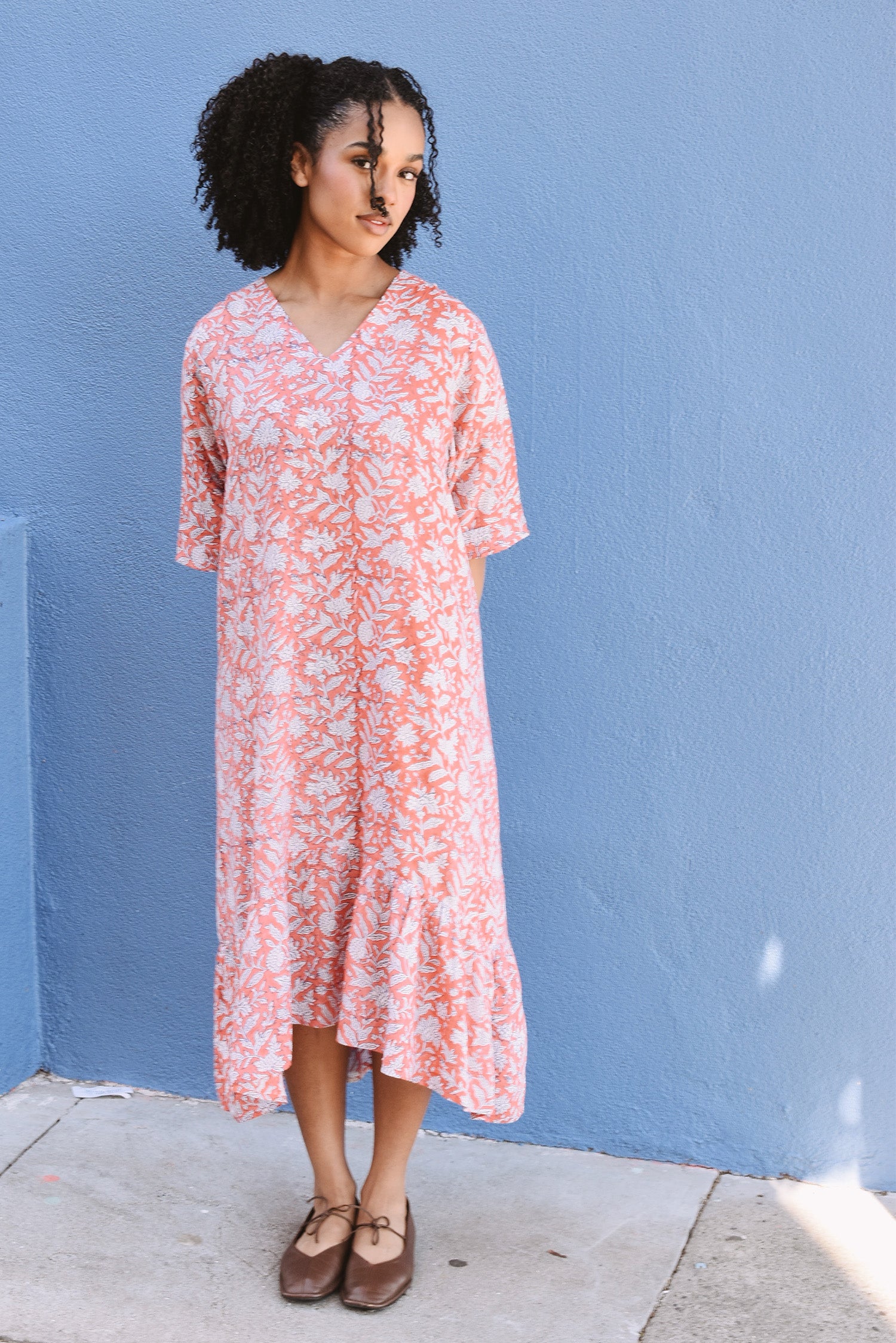Woman wearing a pink floral dress against a blue wall