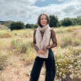 Block printed floral printed chunky wool scarf wrapped around neck, styled with sheer brown long sleeve and denim jeans
