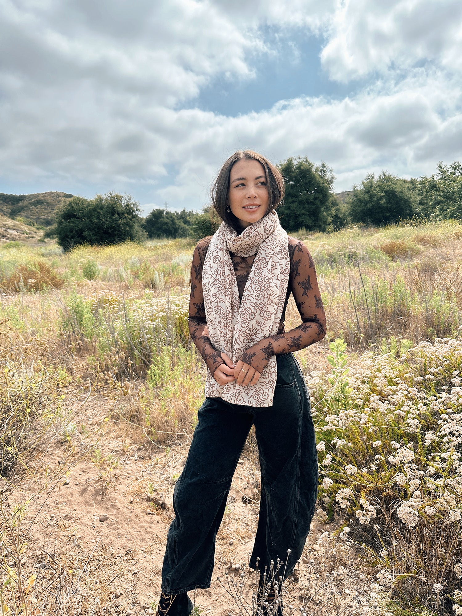 Block printed floral printed chunky wool scarf wrapped around neck, styled with sheer brown long sleeve and denim jeans