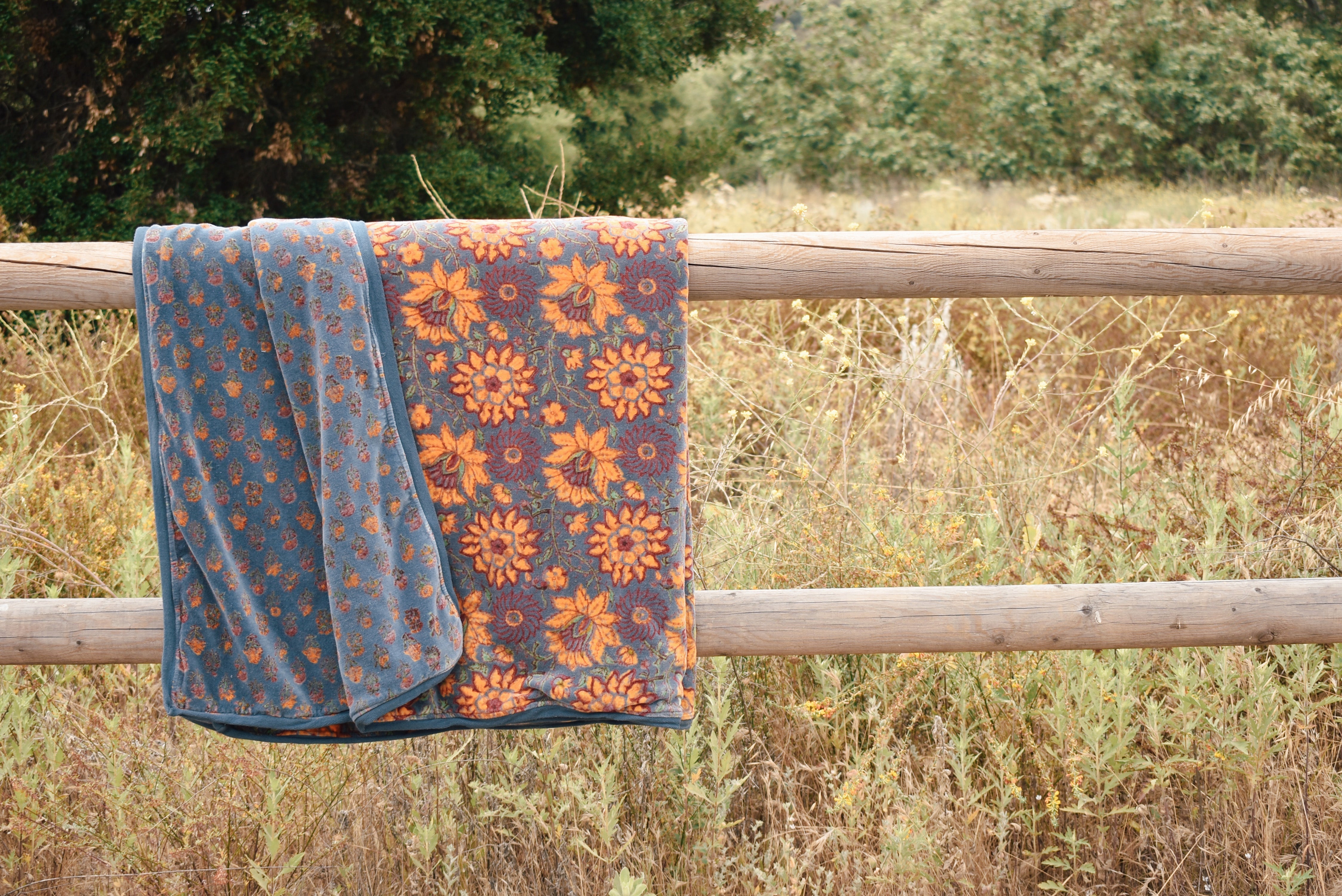 Block printed floral printed velvet blanket hung over a wooden fence