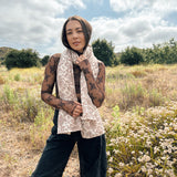 Block printed floral printed chunky wool scarf wrapped around neck, styled with sheer brown long sleeve and black denim jeans