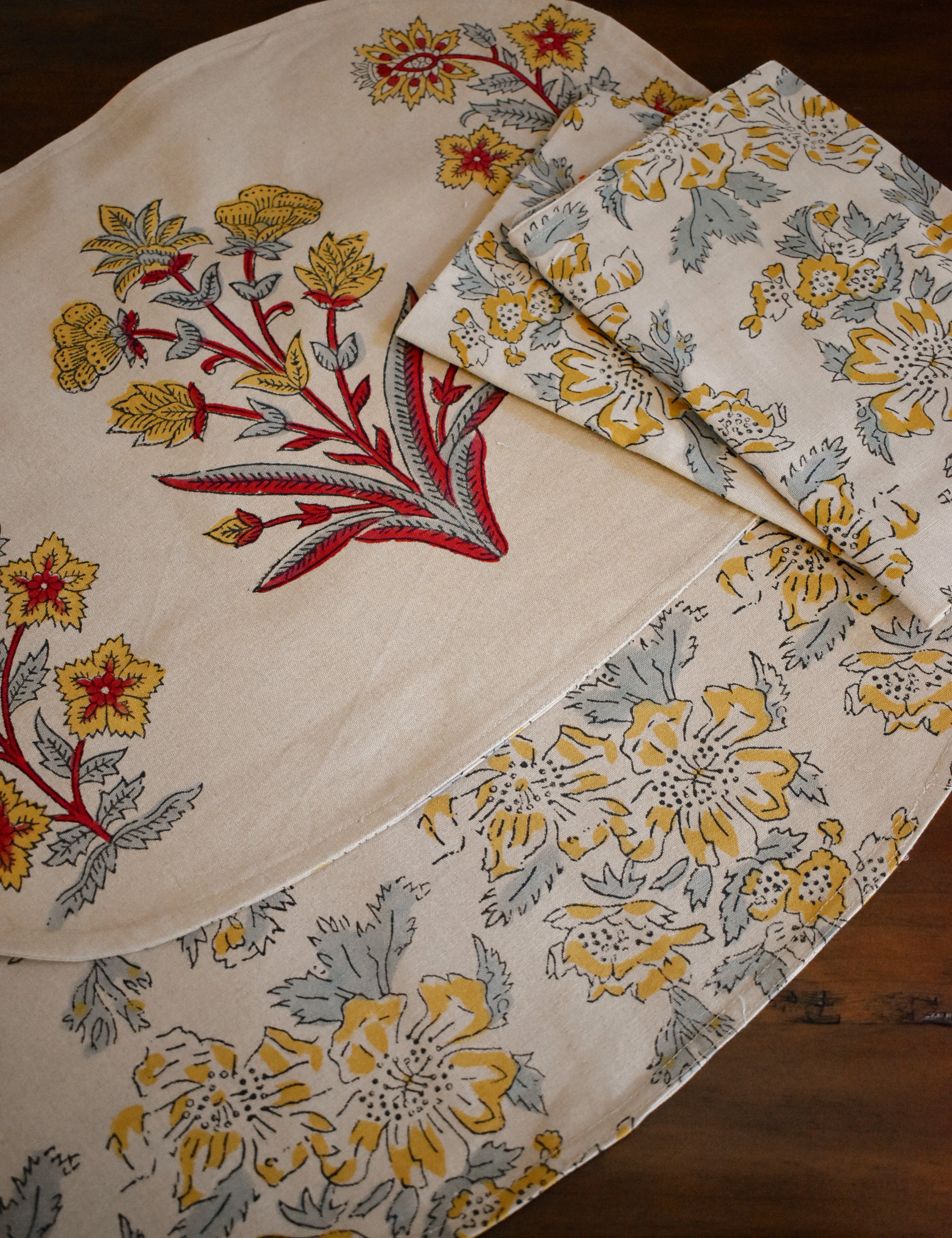 Floral-patterned placemats and napkins on a wooden surface