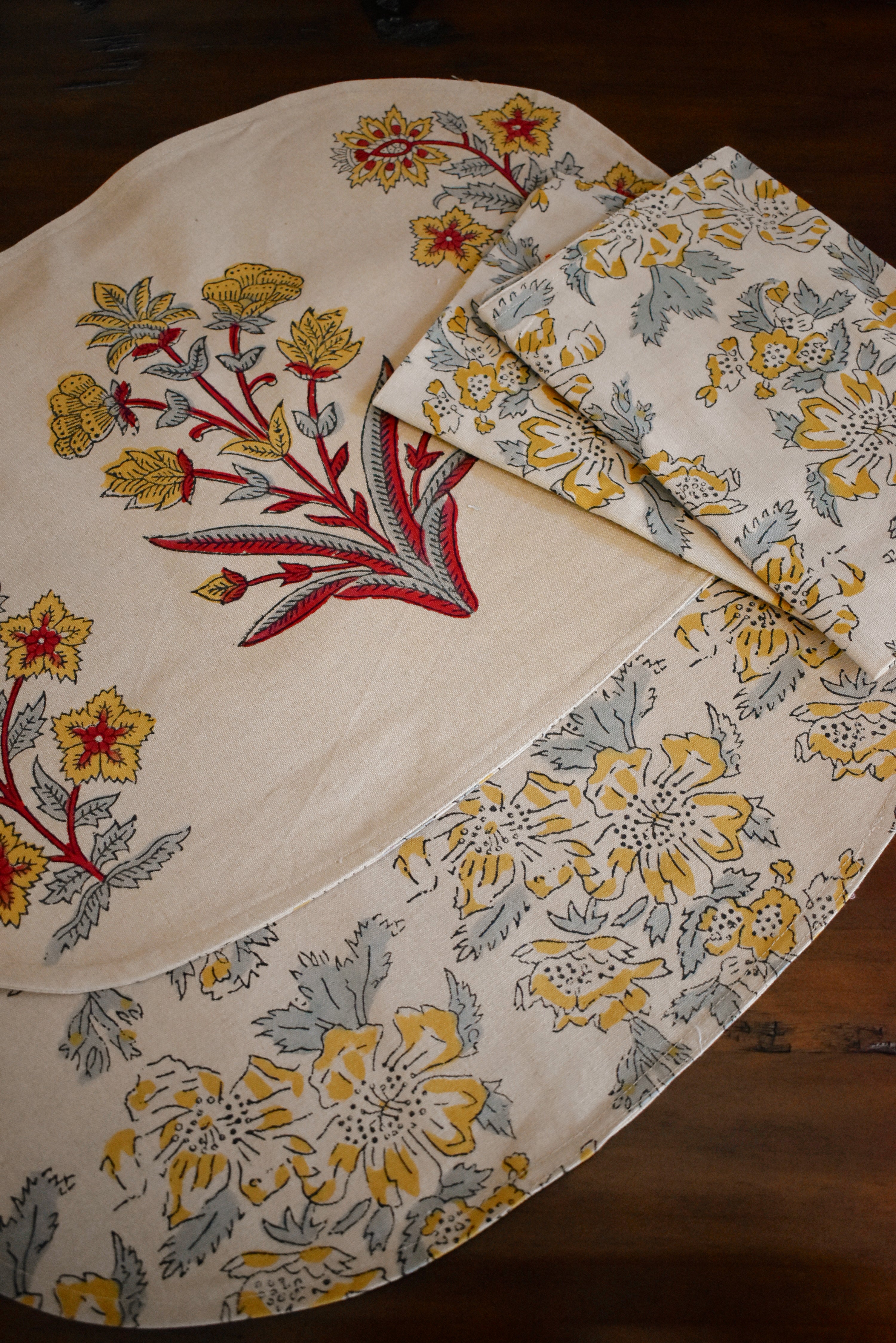 Floral-patterned placemats and napkins on a wooden surface