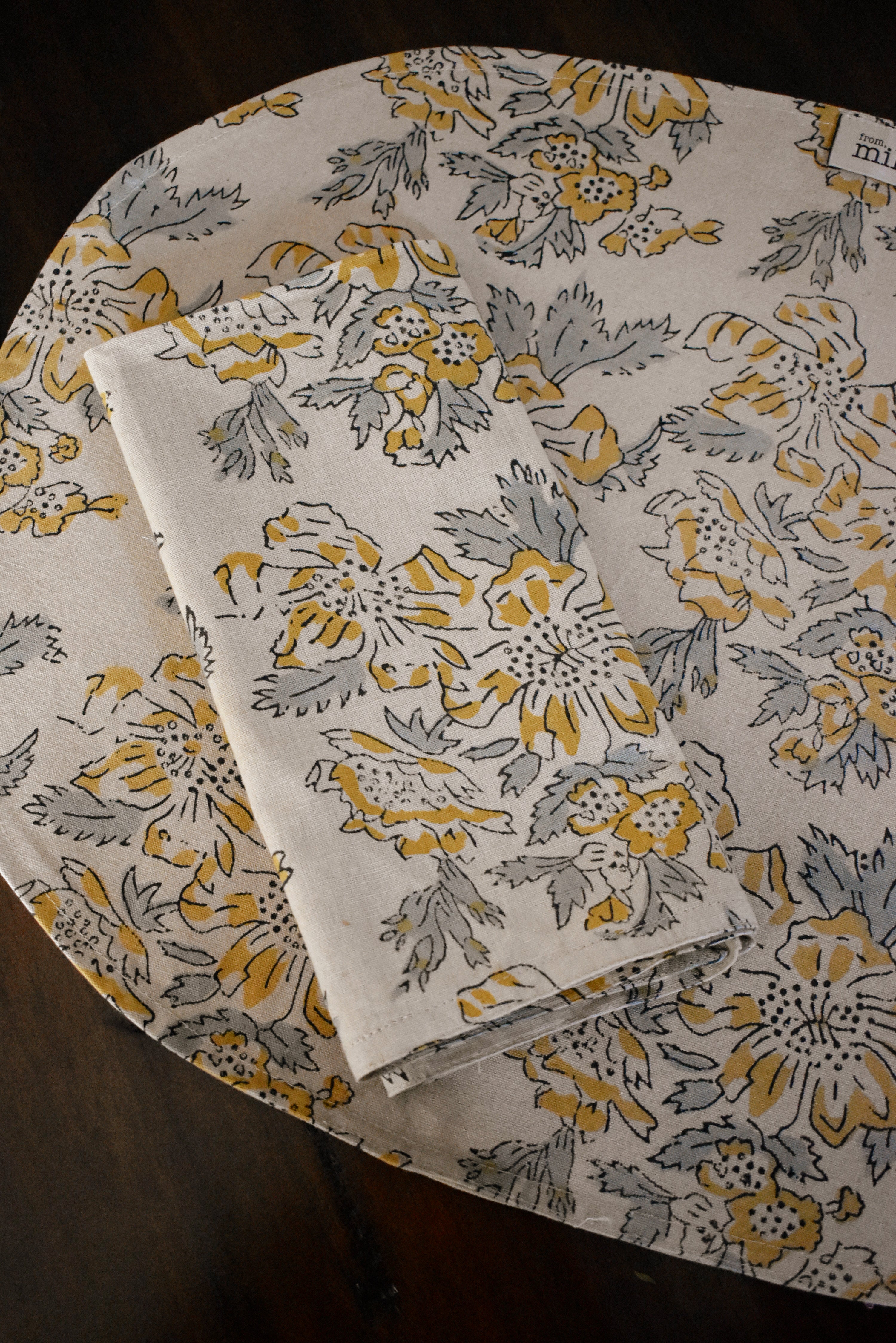 Floral printed placemat with matching table napkin on top, on a wooden surface