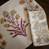 Red, blue and gold floral printed tablecloth and napkin on a wooden surface
