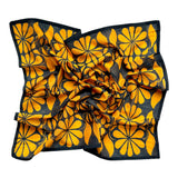 Chai bandana scarf laid flat on white background. Scarf has a blueish black background and large golden floral print allover.