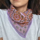 Person wearing a colorful lavender floral patterned bandana scarf on a grey t shirt