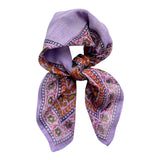 Chamomile bandana scarf tied on white background. Scarf has a lavender background with a green floral border print, and yellow flowers towards the center.