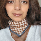 Woman wearing a checkered scarf with a neutral background
