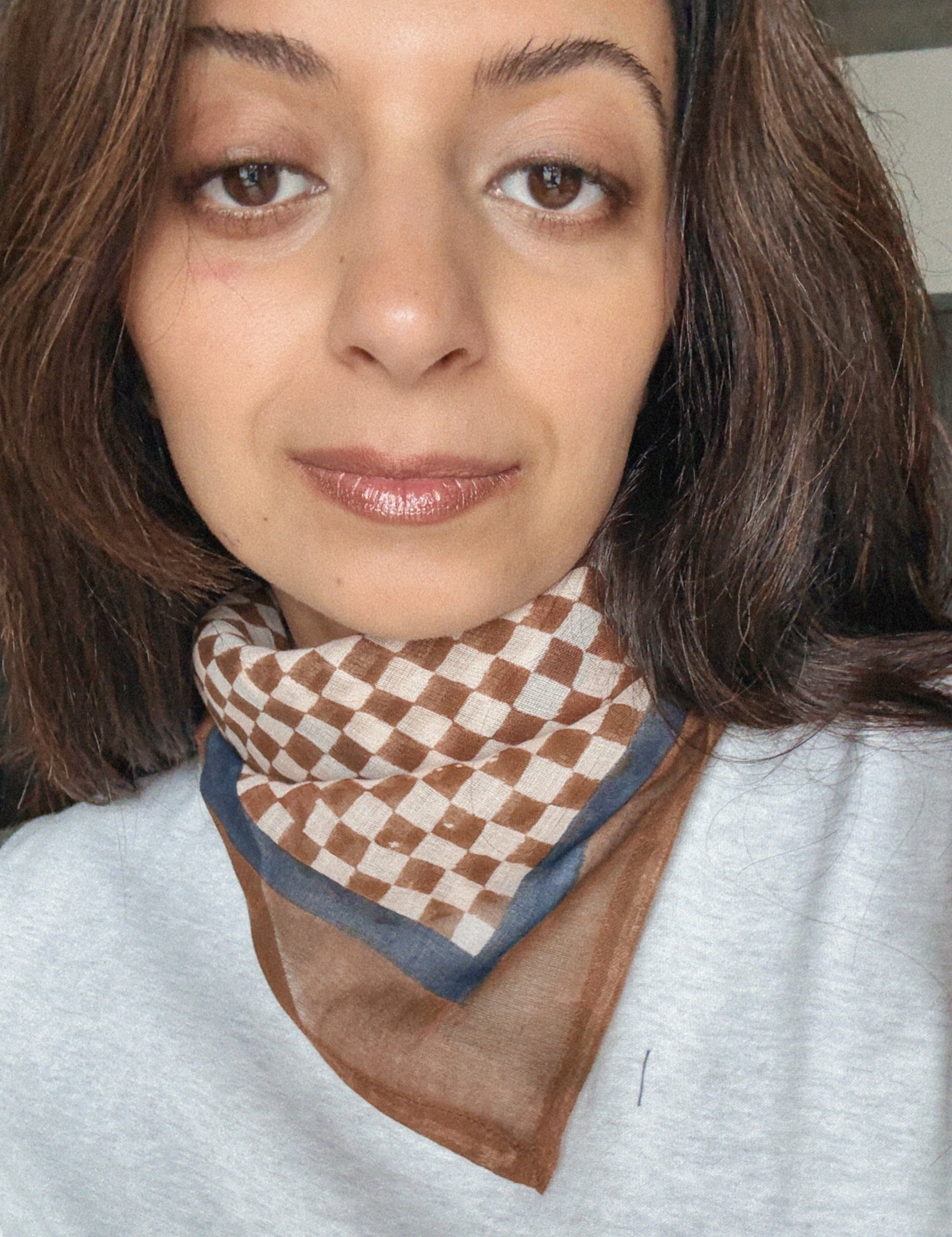 Woman wearing a checkered scarf with a neutral background