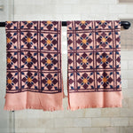 Block printed geometric diamond printed waffle weave khadi hand towels hanging on a shower rod
