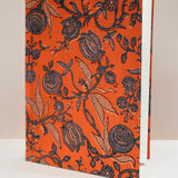 Book with black floral pattern on an orange cover against a beige background