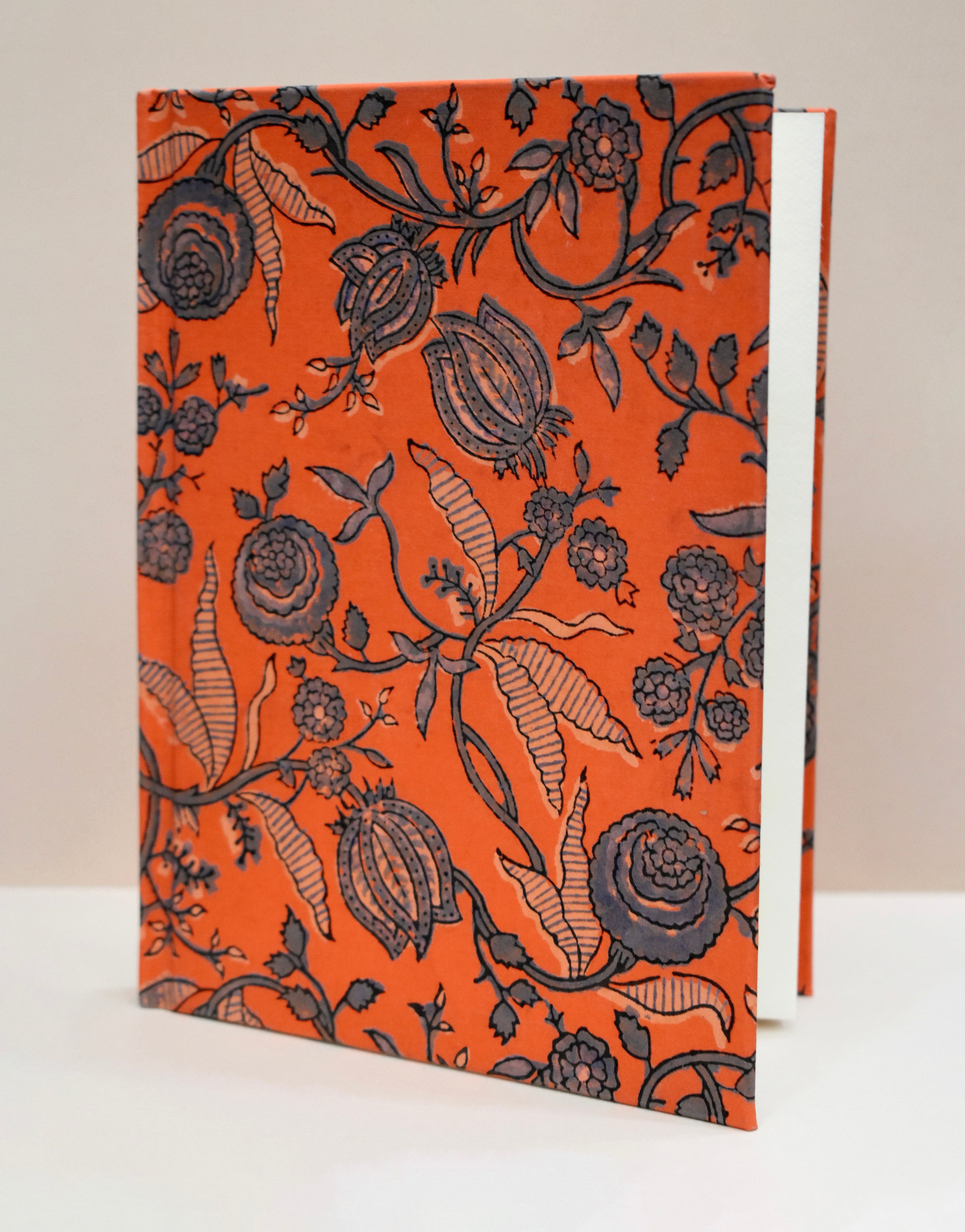 Book with black floral pattern on an orange cover against a beige background