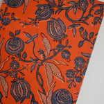 Orange journal with navy floral print on beige background, laid flat, angled shot