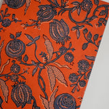 Orange journal with navy floral print on beige background, laid flat, angled shot