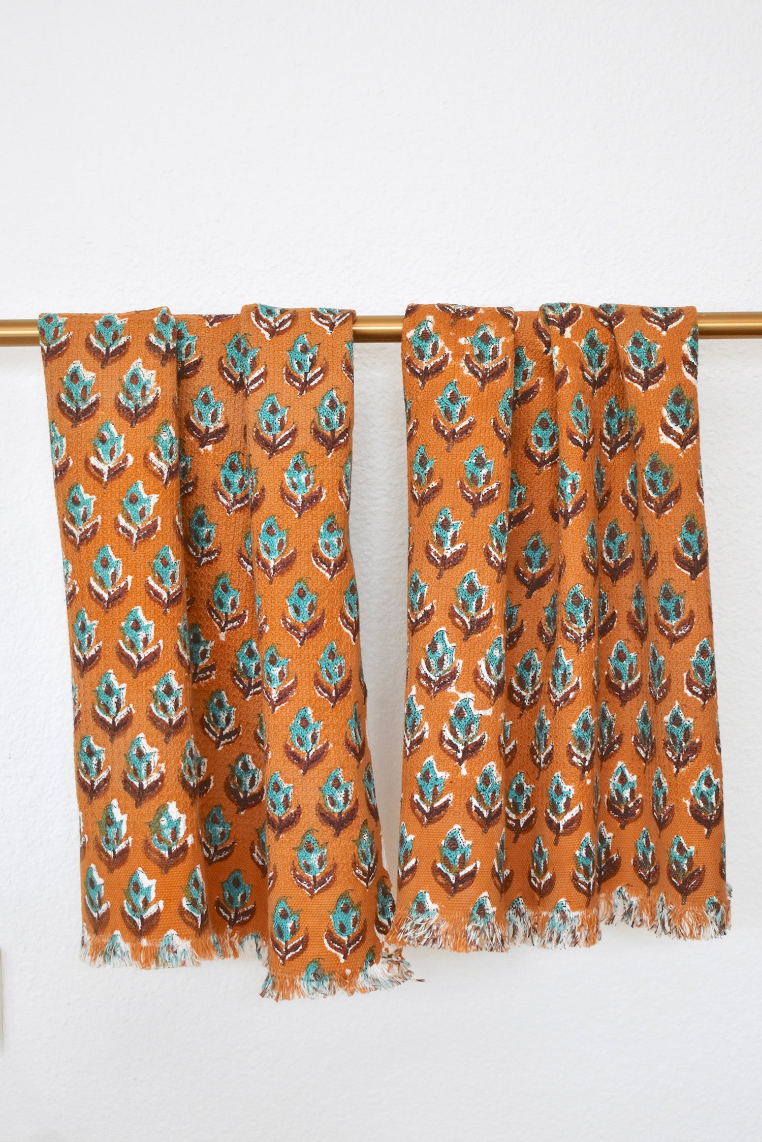 Two Dakota block printed khadi cotton hand towels hanging on a gold bathroom rod