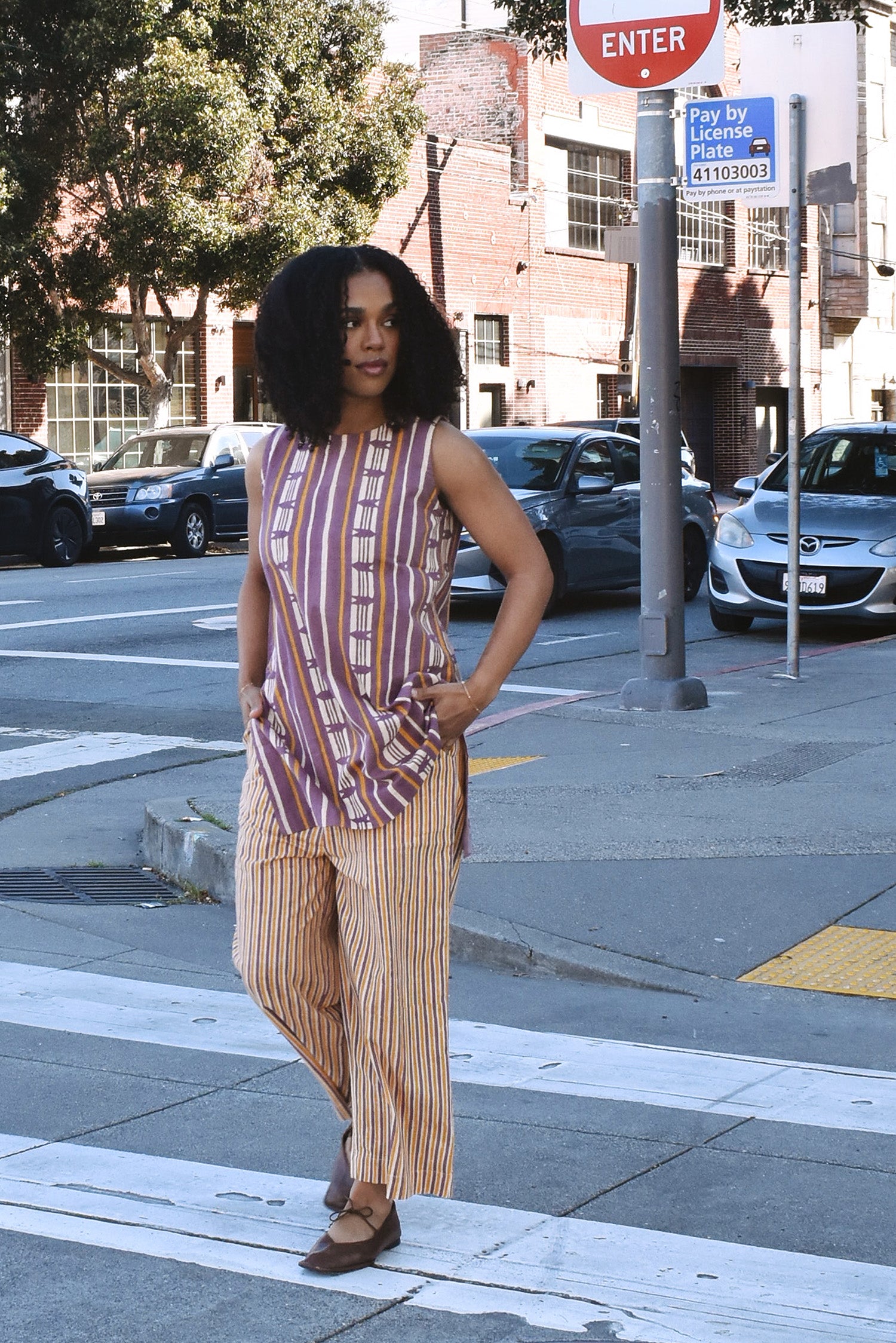Woman in a striped sleeveless top and cropped pant set crossing a crosswalk