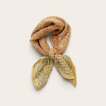 Terracotta Daisy Motif Bandana Scarf styled in a loose neck tie showcasing rust daisy grid print top and charcoal bordered ends on off-white background