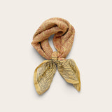 Terracotta Daisy Motif Bandana Scarf styled in a loose neck tie showcasing rust daisy grid print top and charcoal bordered ends on off-white background