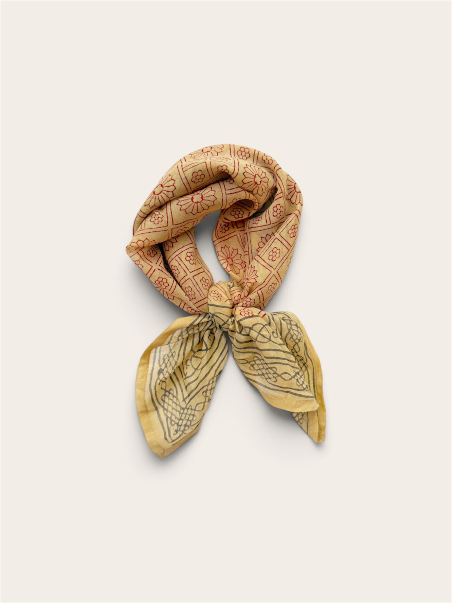 Terracotta Daisy Motif Bandana Scarf styled in a loose neck tie showcasing rust daisy grid print top and charcoal bordered ends on off-white background