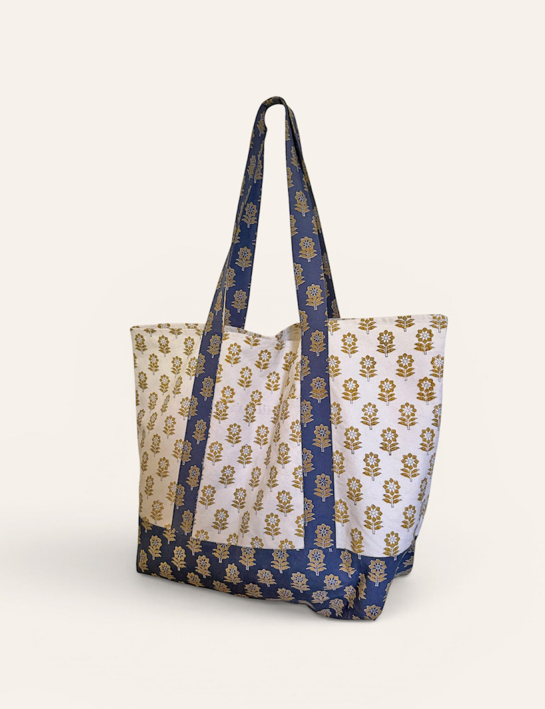 Blue and gold floral printed tote bag standing up against a cream background