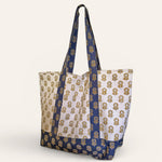 Blue and gold floral printed tote bag standing up against a cream background