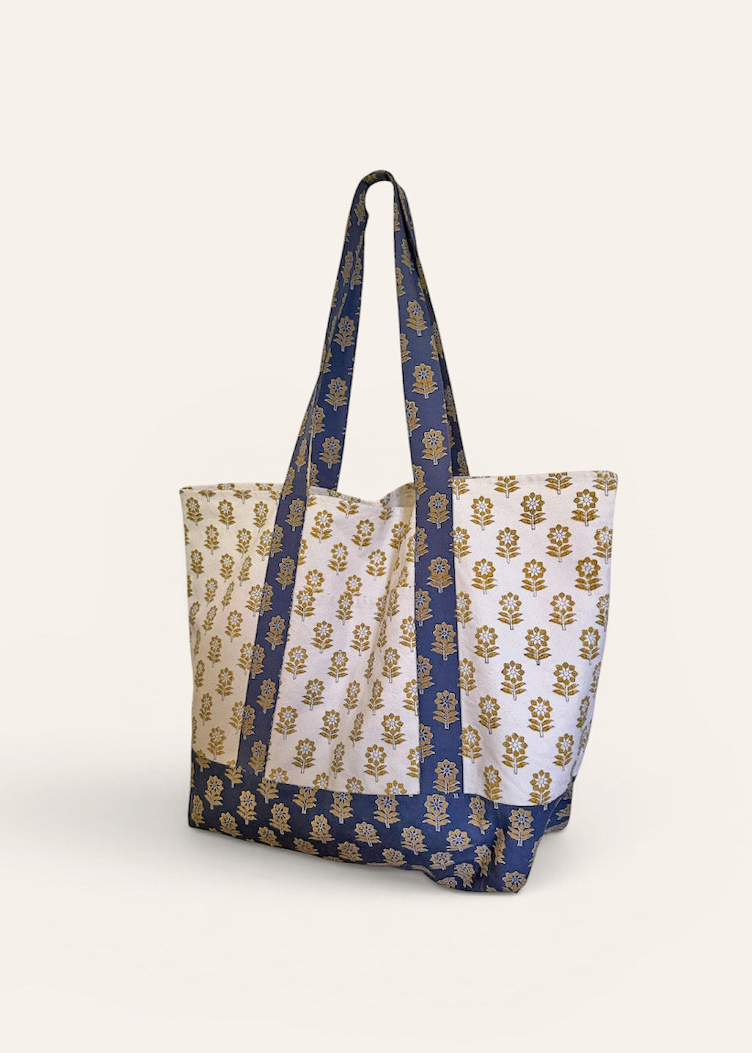 Blue and gold floral printed tote bag standing up against a cream background