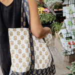 Person holding a floral patterned tote bag in an outdoor market setting