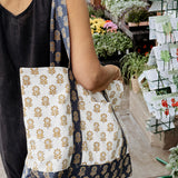 Person holding a floral patterned tote bag in an outdoor market setting