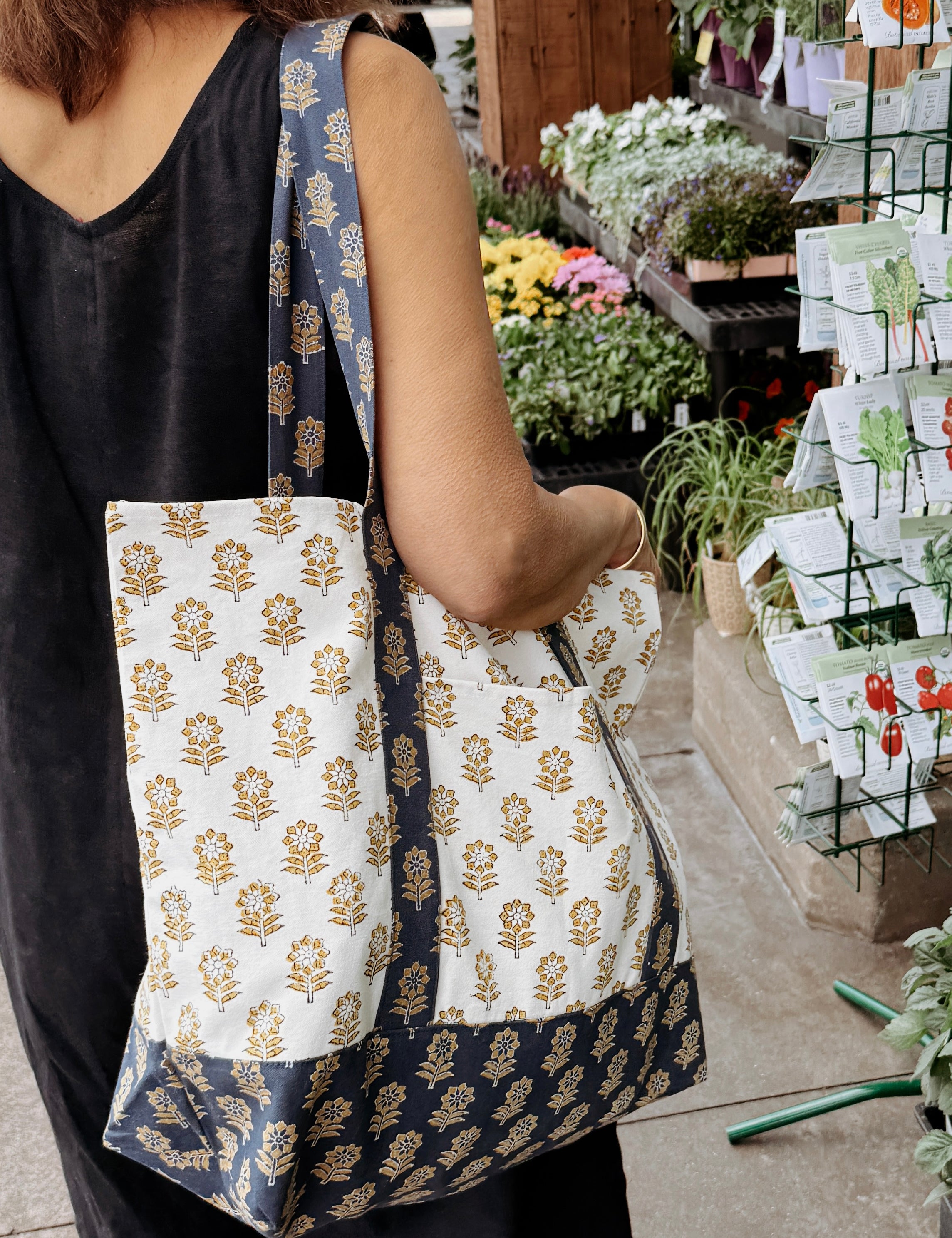 Person holding a floral patterned tote bag in an outdoor market setting