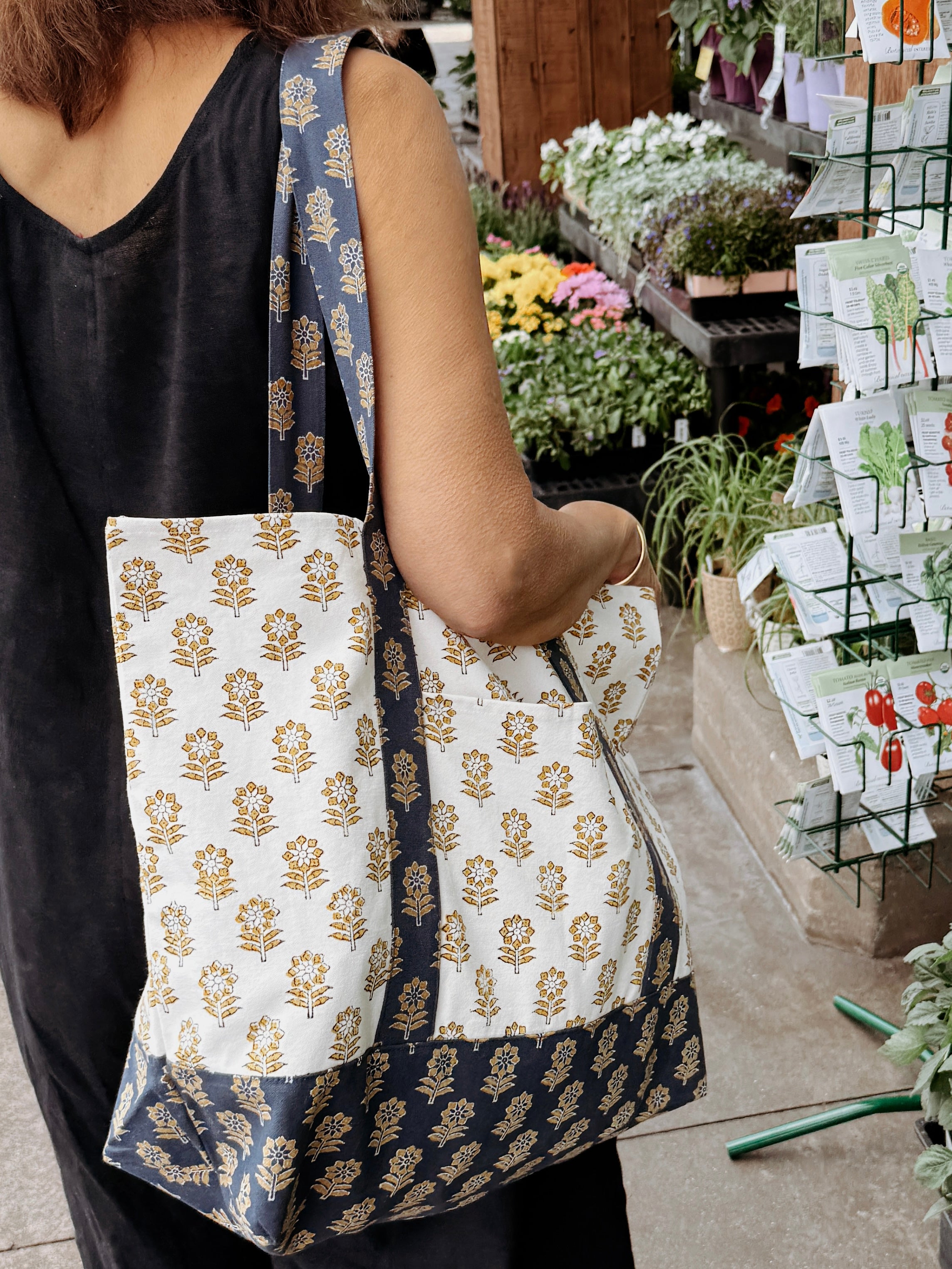 Person holding a floral patterned tote bag in an outdoor market setting