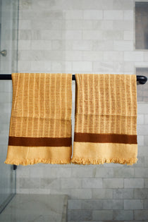 Block printed Feliz hand towels hanging on a black rod outside a shower