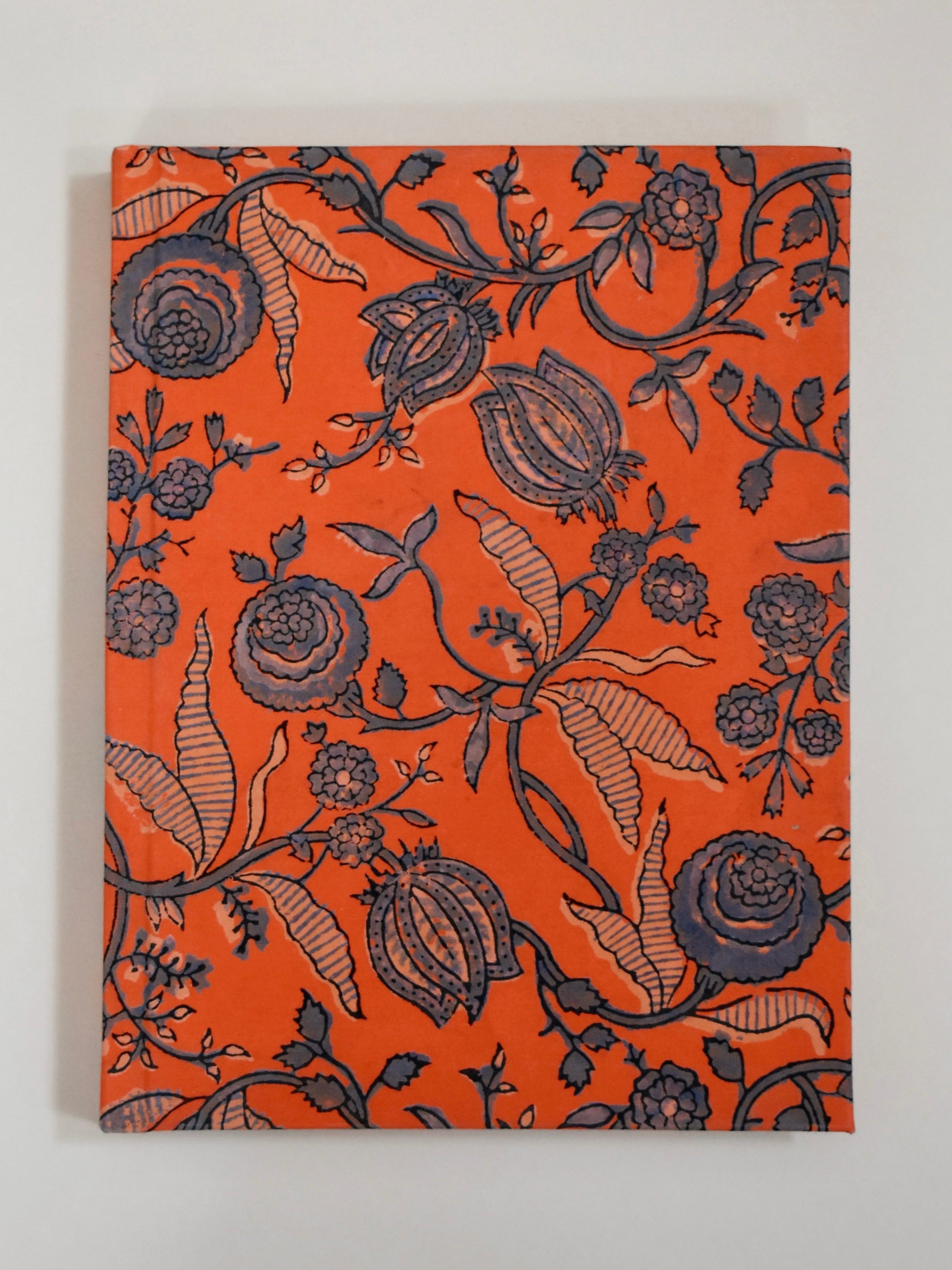 Floral patterned notebook with dark navy floral design on an orange background