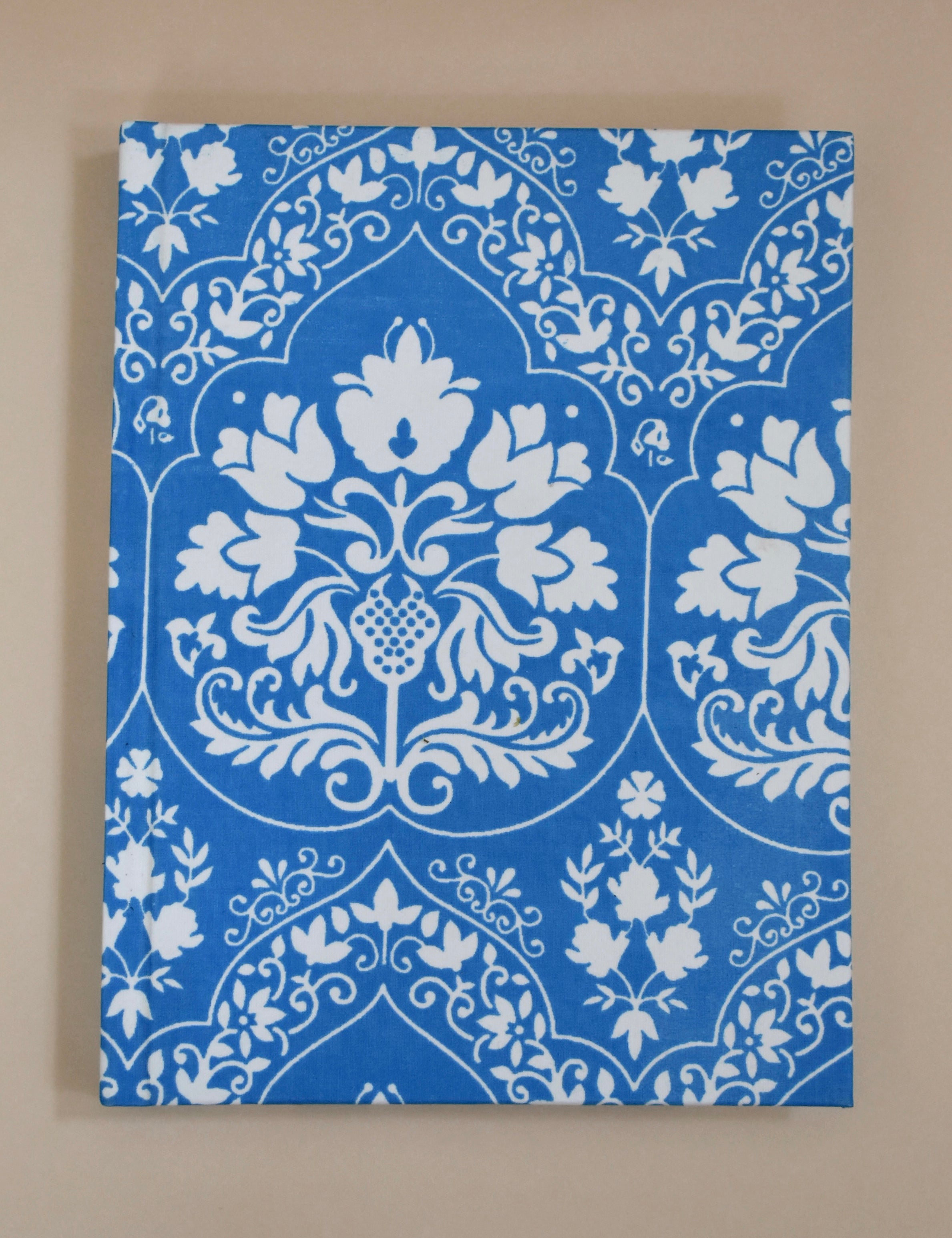 Blue and white floral patterned journal on a beige background