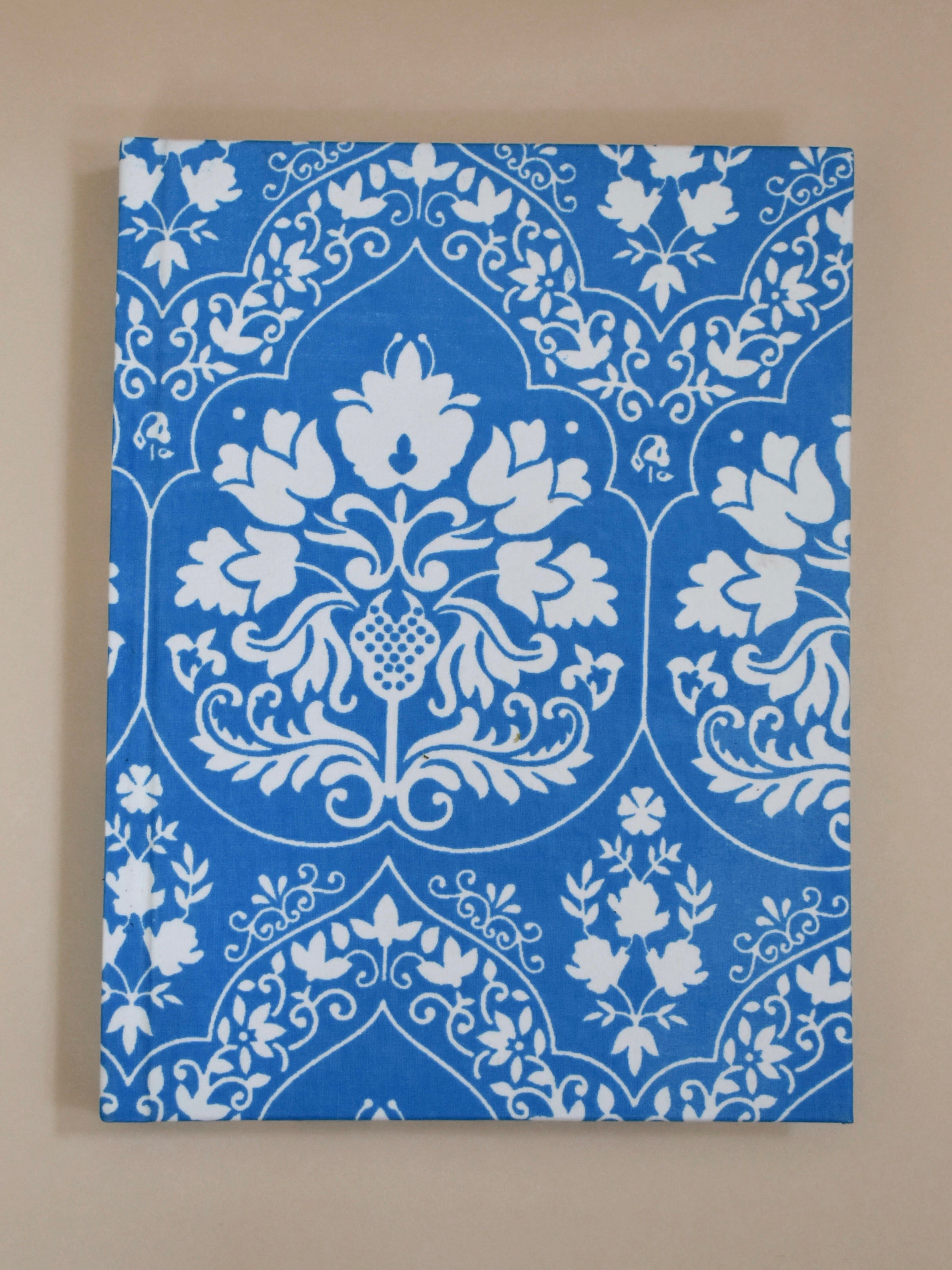 Blue and white floral patterned journal on a beige background
