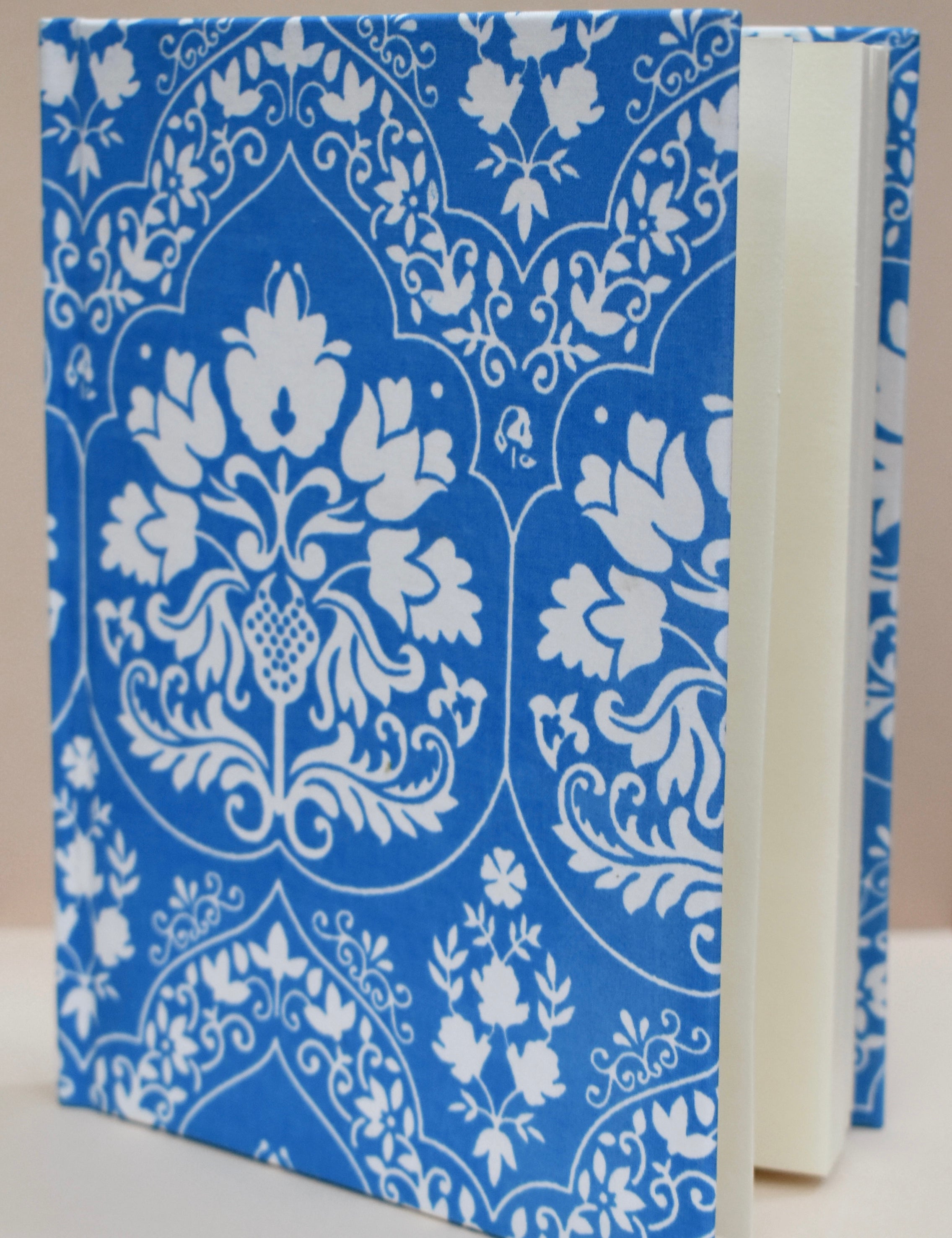 Blue notebook with white floral-patterned journal against a beige background