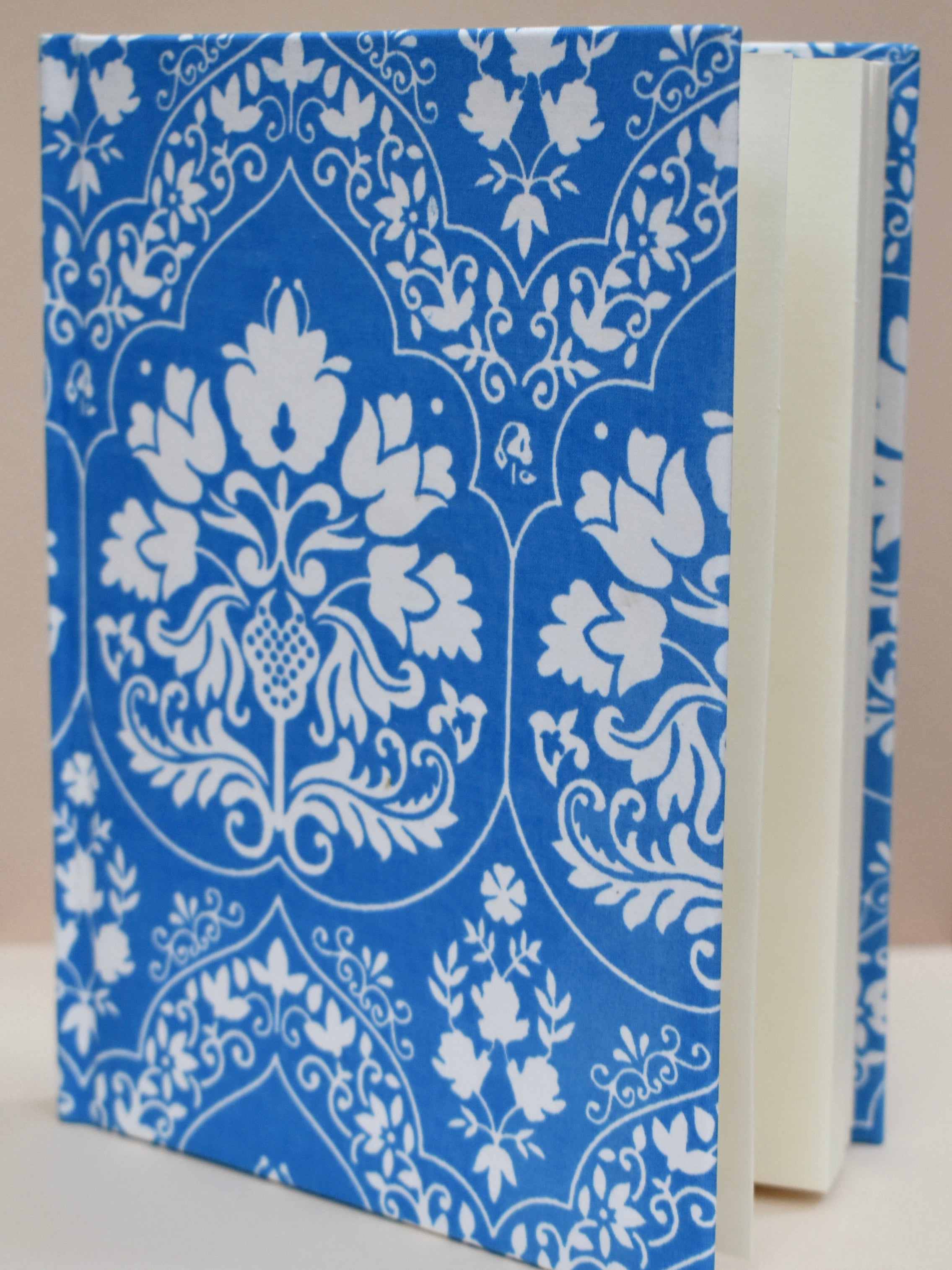 Blue notebook with white floral-patterned journal against a beige background
