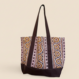 Brown and gold floral printed tote bag standing up against creamish yellow background