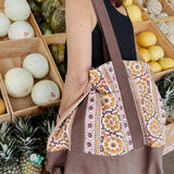 Woman wearing brown and gold floral printed tote bag while shopping for groceries