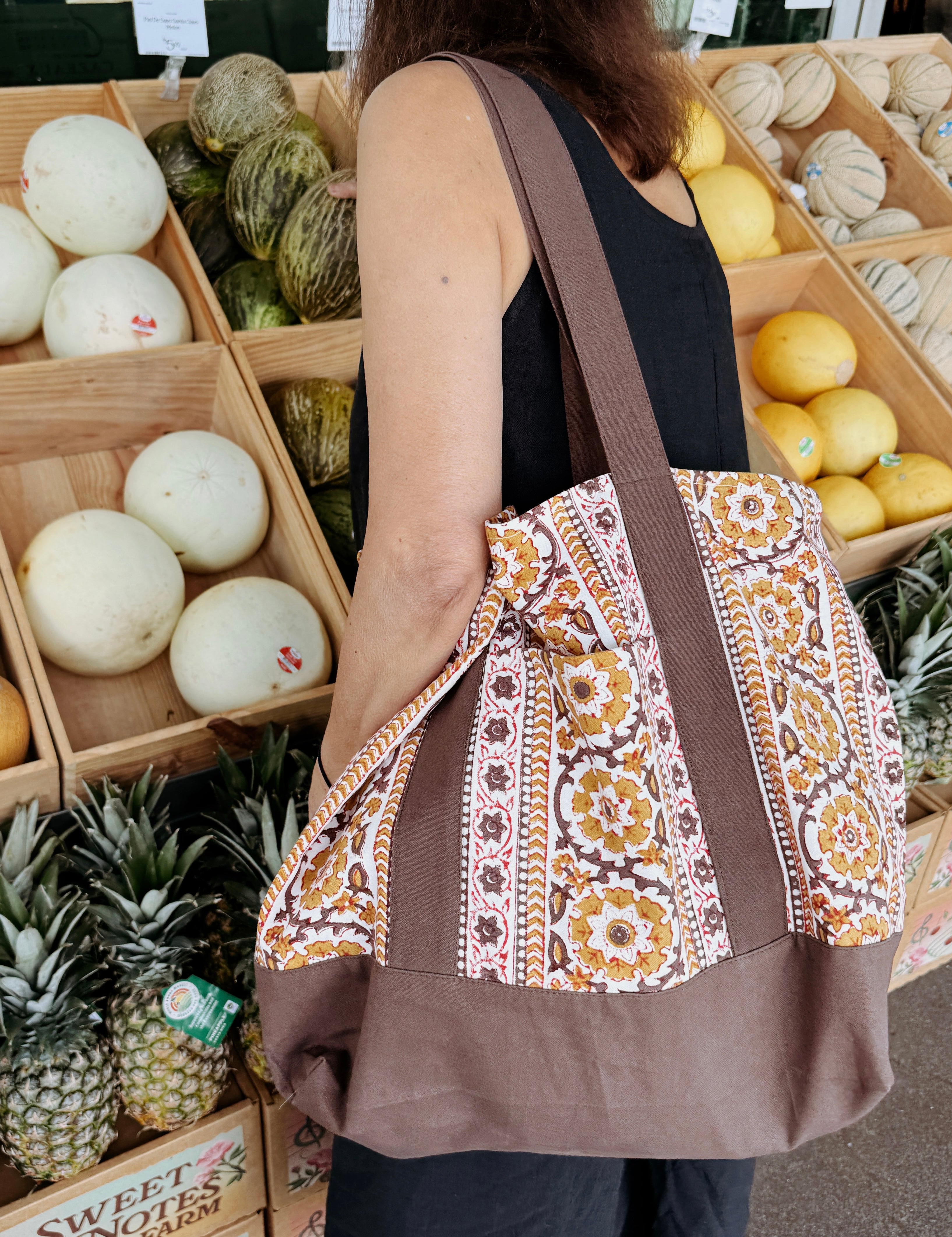 Woman wearing brown and gold floral printed tote bag while shopping for groceries