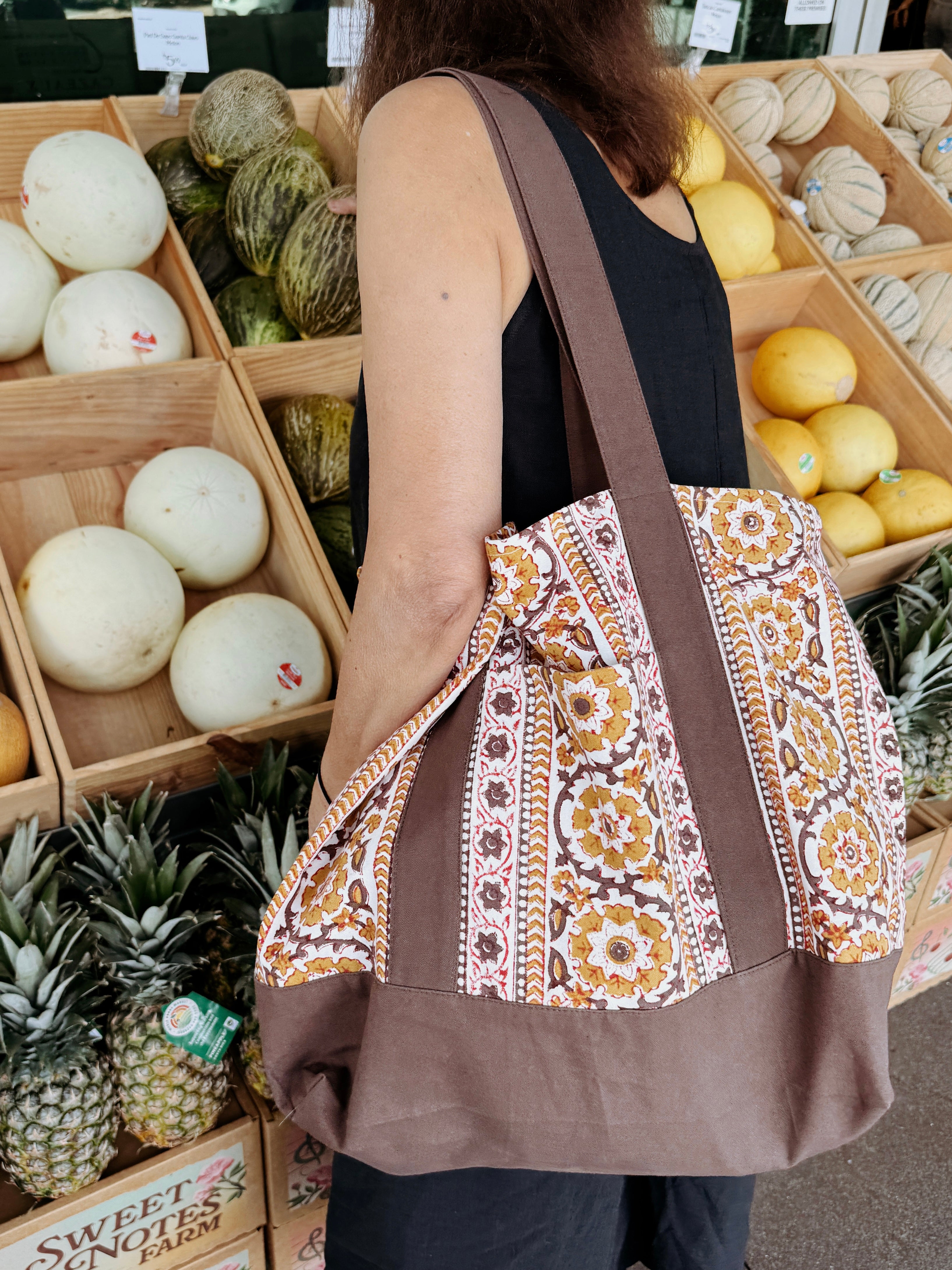 Woman wearing brown and gold floral printed tote bag while shopping for groceries