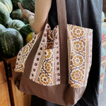 Woman wearing brown and gold floral printed tote bag while shopping for melons