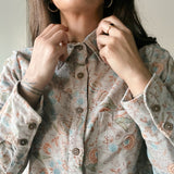 Woman buttoning up Helena corduroy floral printed shirt, close up on buttons