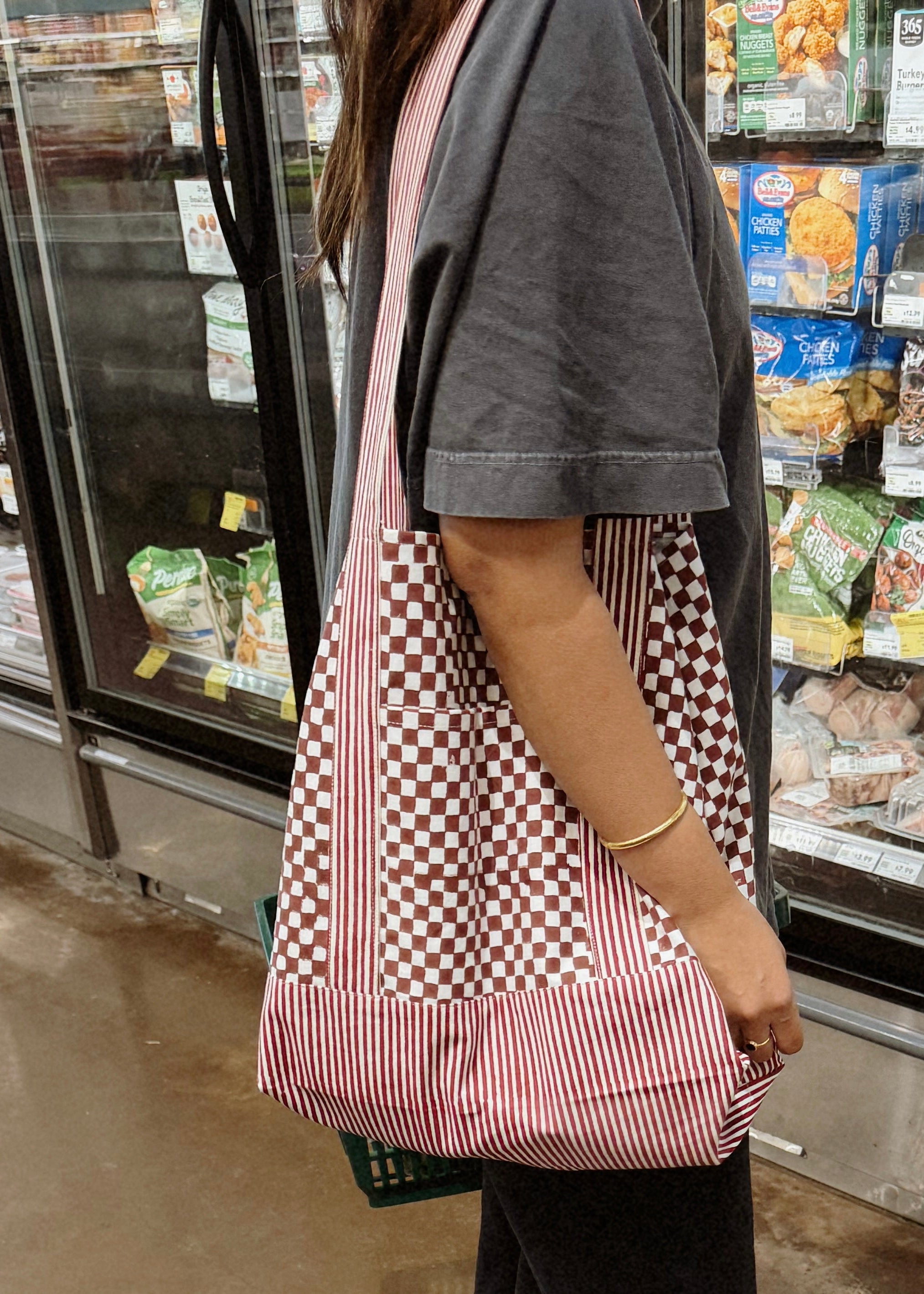 Woman wearing red checkered and striped tote bag in grocery store