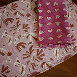 Large floral printed placemat with purple floral printed table napkin on a wooden table