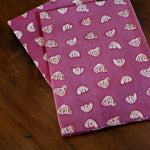 Two purple table napkins with floral print folded on wooden table