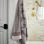 Block printed striped khadi bath towel hanging on a shower hook